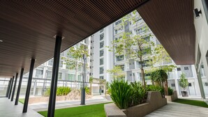 A modern building with a covered walkway, greenery, and a view of high-rise buildings. - FOX Hotel Glenmarie Shah Alam (Shah Alam)