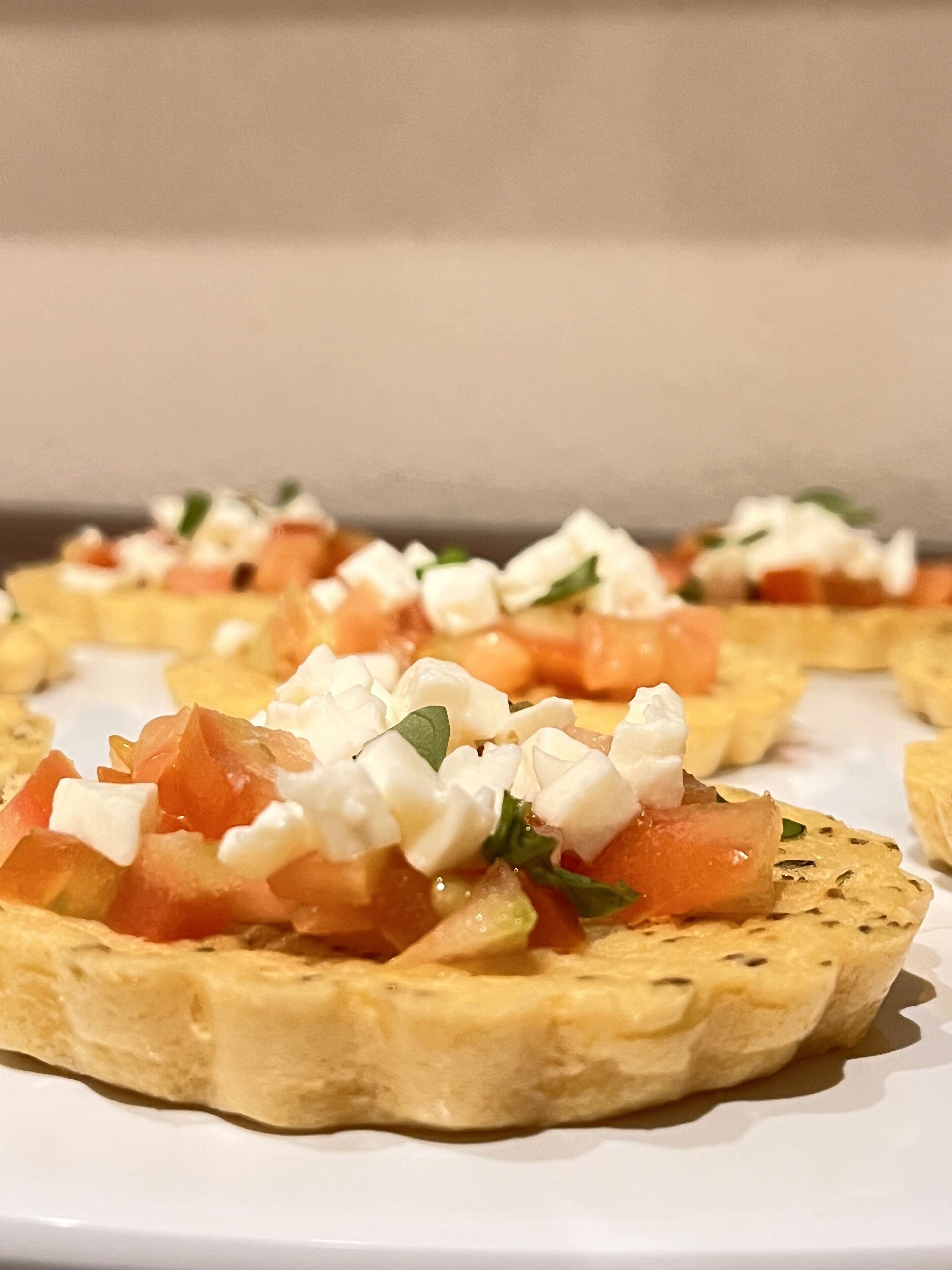 Une assiette de tostadas garnies de fromage, de tomates et d’herbes aromatiques.