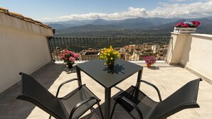 A balcony with a table and chairs, a potted plant, and a view of distant mountains. - Goloritzè Room and Breakfast (Baunei)
