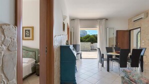 Une chambre comprenant un lit, une commode, une table à manger avec des chaises et donnant sur l’extérieur.