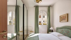 Une chambre à coucher avec un lit, une chaise, une table et une fenêtre avec des rideaux.