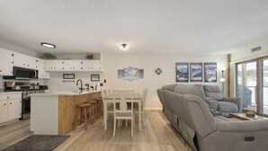 A modern kitchen with white cabinets, a central island, and a dining area with white chairs. - Newly remodeled condo w/access to shared hot tub & sauna ON SHUTTLE ROUTE (Fraser)
