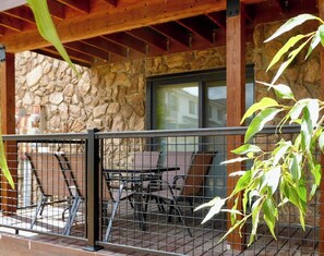A covered patio with stone walls, a wooden ceiling, and a metal railing.