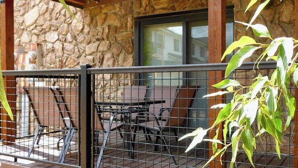 A covered patio with stone walls, a wooden ceiling, and a metal railing. - Newly remodeled condo w/access to shared hot tub & sauna ON SHUTTLE ROUTE (Fraser)