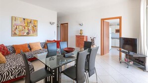 A modern living room with a glass dining table, black chairs, a zebra-patterned sofa, and a painting on the wall. - 1694 Villa Michelle - Appartamento 4 (Porto Cesareo)