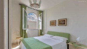 A bedroom with a bed, a chair, a nightstand, and two framed pictures on the wall. - 1694 Villa Michelle - Appartamento 4 (Porto Cesareo)