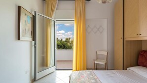 A bedroom with a bed, a chair, a wardrobe, a door leading to a balcony, and a framed picture on the wall. - 1694 Villa Michelle - Appartamento 4 (Porto Cesareo)