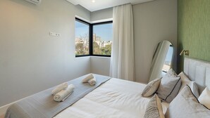 A hotel room with a large bed, a window with a view of buildings, a mirror, and a green accent wall. - GuestReady - Urban Comfort near Clérigos Tower (Porto)