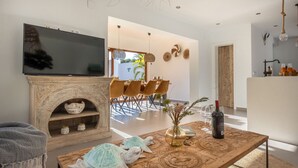 Un salon moderne doté d’une cheminée, d’un téléviseur, d’un coin repas avec des chaises et d’une table basse agrémentée d’objets décoratifs.