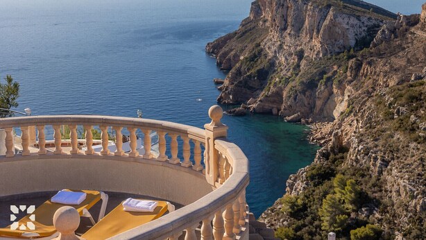 Un balcone con vista sul mare e su una scogliera rocciosa.
