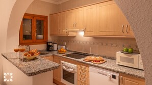 Una cucina funzionale con piani di lavoro in granito, mobili in legno, forno integrato e microonde.