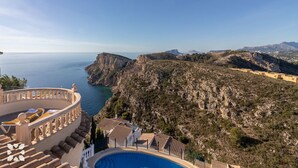 Un hotel sulla costa con piscina, balconi a terrazza e vista sul mare e sulle scogliere.