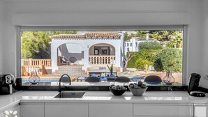 Eine moderne Küche mit einem großen Fenster, das auf eine Terrasse blickt.