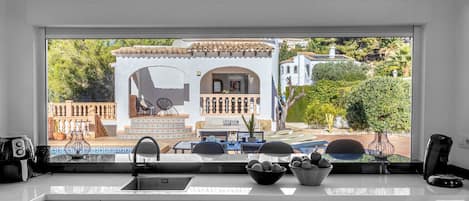 Een moderne keuken met een groot raam dat uitkijkt op een patio.