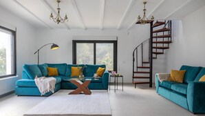 Un salon moderne avec des canapés turquoise, un tapis blanc et un escalier en colimaçon.