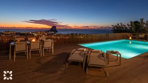 Une piscine sur le toit, offrant une vue sur les gratte-ciel de la ville et sur une montagne au coucher du soleil.