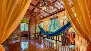 A hammock in a wooden room with a view of trees. - Caribe Town Bungalows (Cahuita)