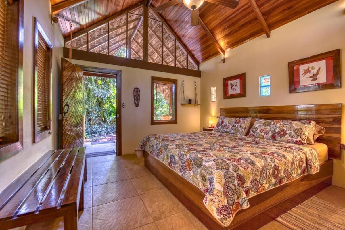 Un dormitorio con cama de madera, un banco y vistas al exterior.