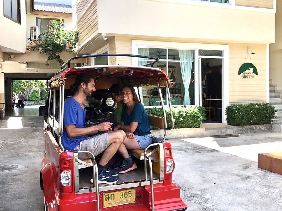 A red tuk-tuk parked in front of a building with a sign reading "HOME ROMYEN".