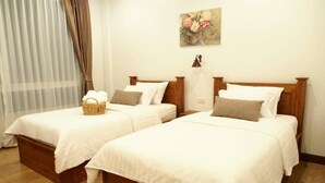A hotel room with two wooden beds, white bedding, a wicker basket on one bed, and a floral painting on the wall. - Romyen cafe homestay (Ayutthaya)