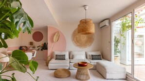 A modern living room with a white sofa, a round coffee table, and a hanging woven light fixture. - ARIA - Penthouse & Garden (Roma)