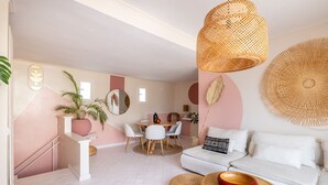 A modern living room with a white sofa, a dining area with a round table, and a kitchen in the background. - ARIA - Penthouse & Garden (Roma)
