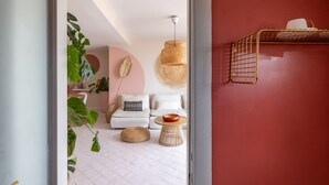 A modern living room with a white sofa, a round coffee table, and a hanging wicker lamp. - ARIA - Penthouse & Garden (Roma)