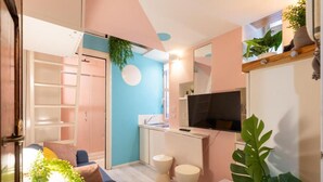 A compact living space with a kitchenette, a TV, and a large plant. - Romantic Rome Retreat, Steps from Colosseum (Roma)