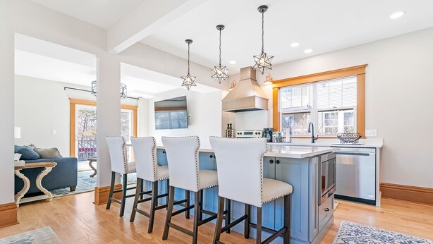 A modern kitchen with a central island, bar stools, and pendant lighting.