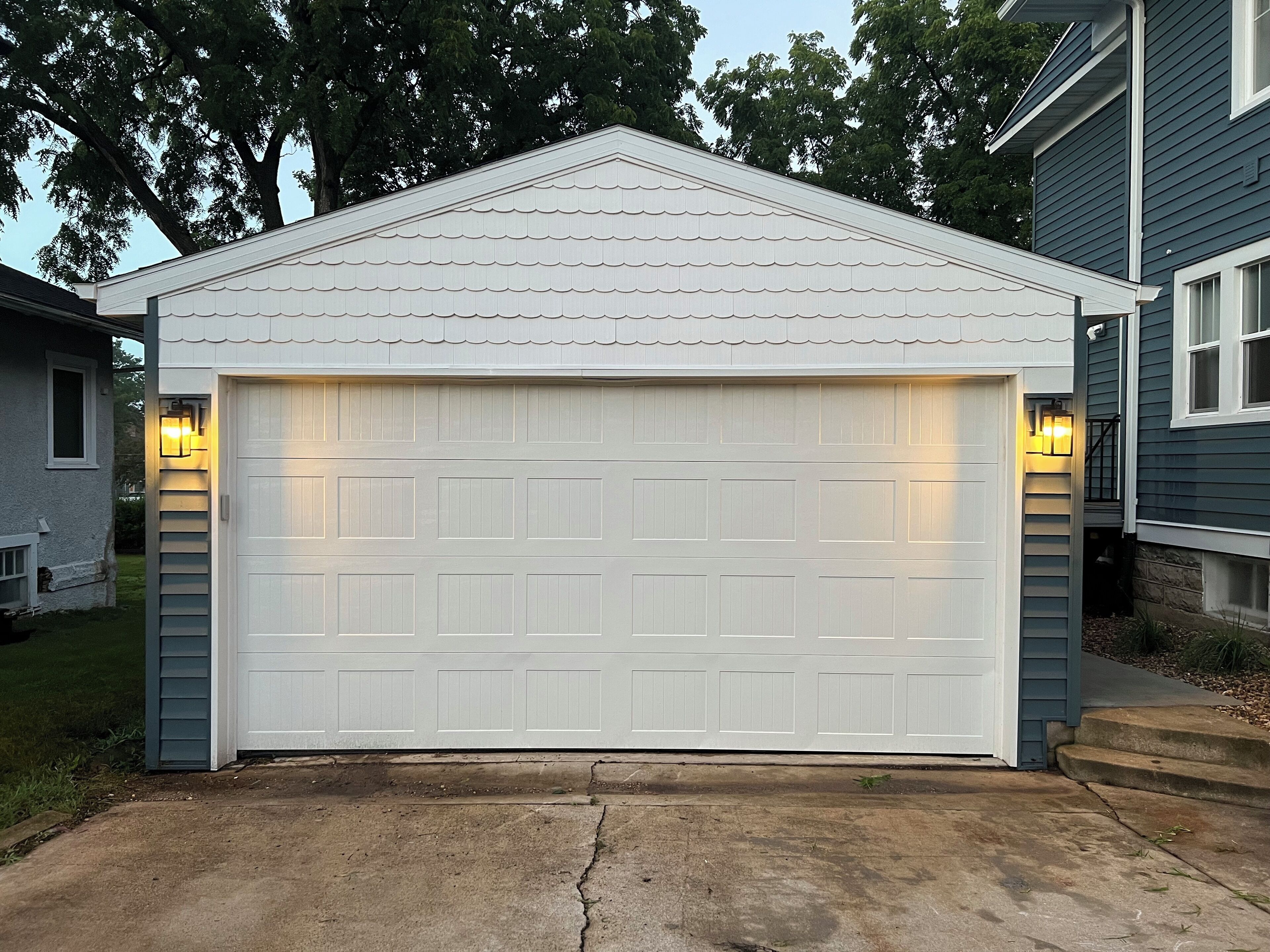 Een garage met een witte deur en twee wandlampen.