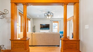 A hallway with wooden columns, a beige sofa, and a ceiling light fixture.