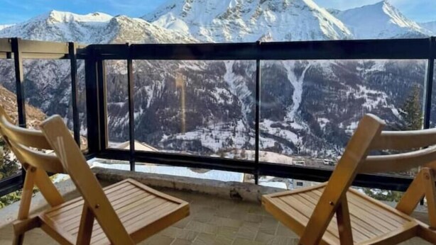 Ein Balkon mit zwei Holzstühlen und Blick auf die Berge.