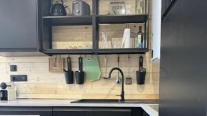 Eine moderne Küche mit schwarzen Schränken, einer Holz Arbeitsplatte und einer eingebauten Spüle.
