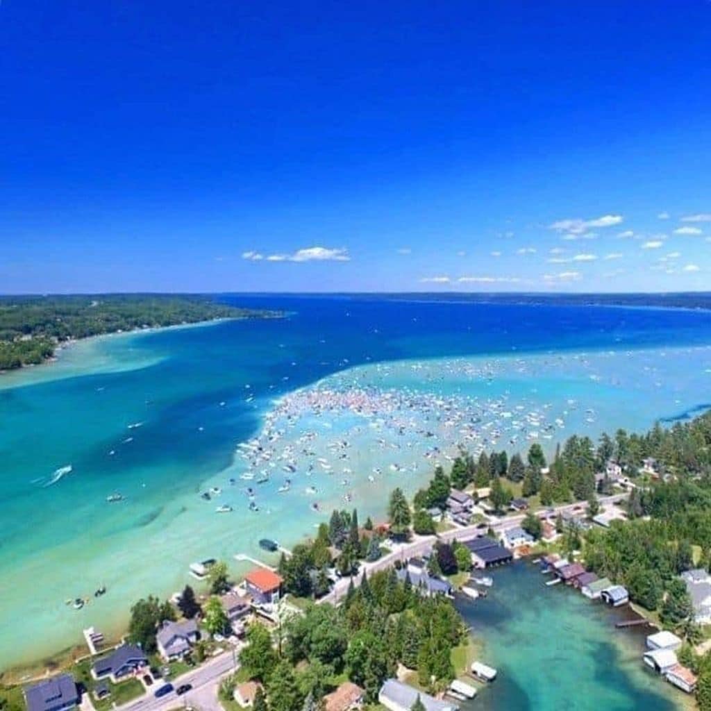 A coastal residential area with houses, a clear blue sea, and boats.