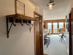 A hallway with a wooden shelf, a framed sign, and a dining area with a table and chairs. - Private Cabin with Lake Views Near Torch Lake, Fire Pit & Boat Parking (Rapid City)