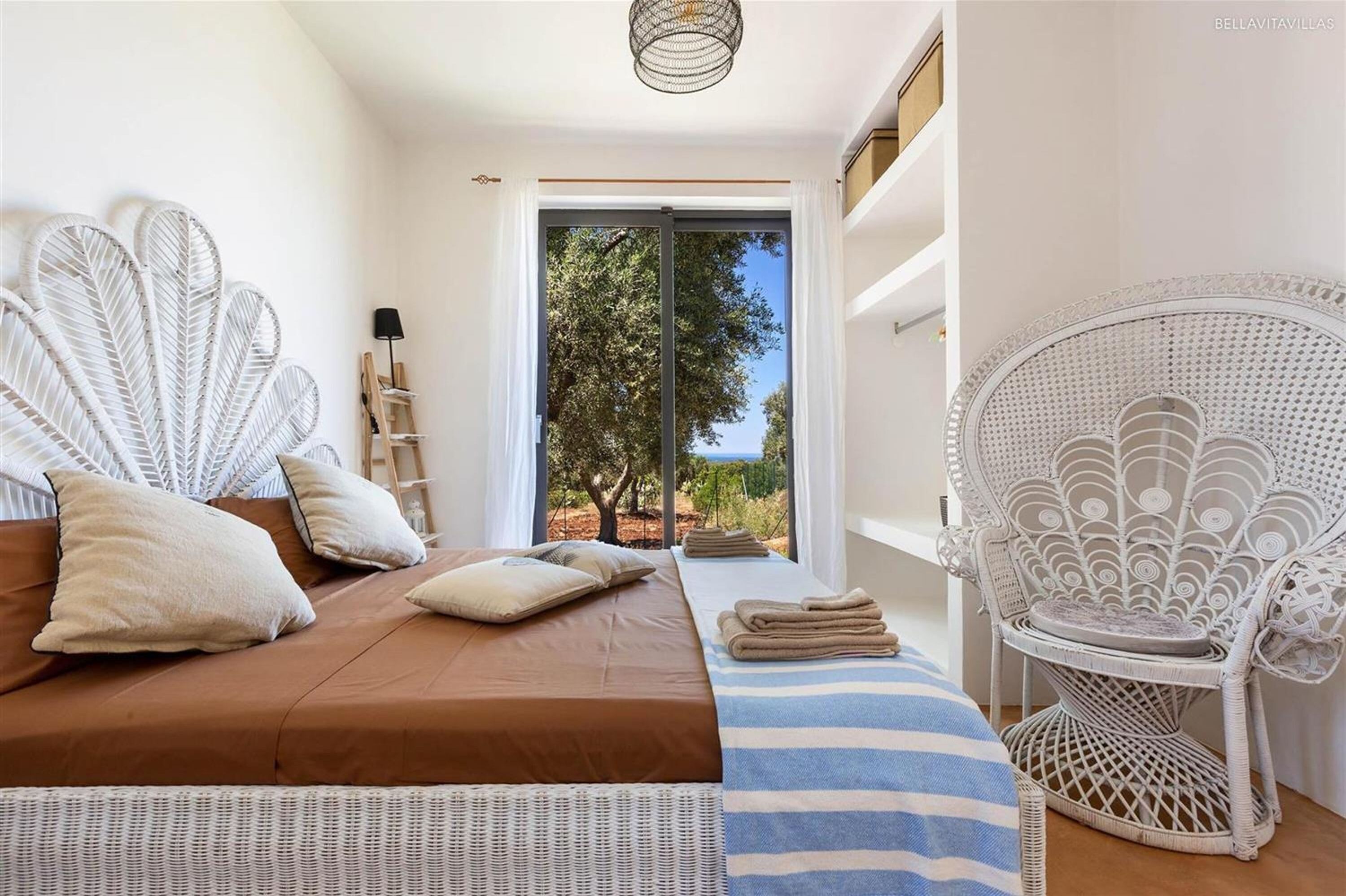 Un dormitorio con cama, una silla, vistas a árboles y una puerta que da al exterior.