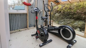 Ein Heimfitnessraum mit einem Crosstrainer, einem stationären Fahrrad und einem Rudergerät.