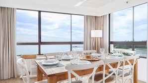A dining area with a table set for four, large windows, and a view of the sea. - Royal Palms Uninterrupted Views (Palm Beach)