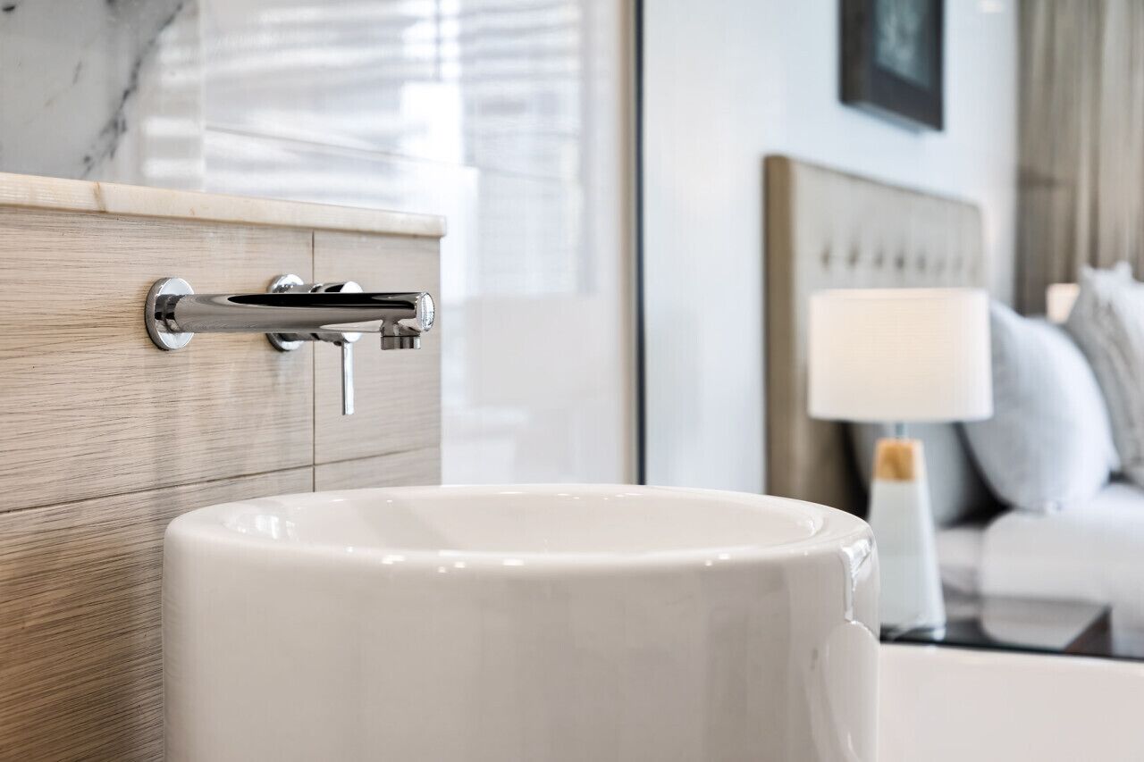A modern bathroom with a white sink, chrome faucet, and wooden paneling.
