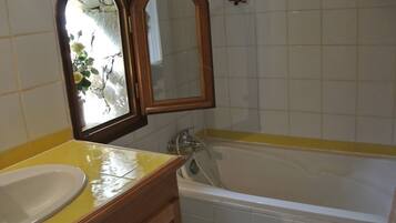 Une salle de bain avec une baignoire, un lavabo et deux miroirs.