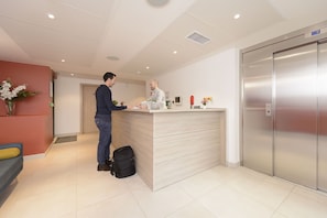 A reception area with a counter, a desk, and a modern elevator.