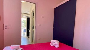 Ein Zimmer mit rotem Teppich, einem Bett und zwei zusammengerollten Handtüchern auf dem Boden.