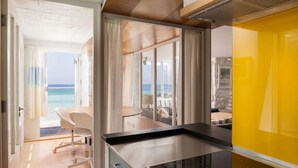 A modern interior with a view of the sea, a dining area, and a yellow accent wall. - Old Saltings, overlooking Porthmeor beach (St Ives)
