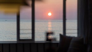 A sunset over the ocean viewed through a window with a railing. - Old Saltings, overlooking Porthmeor beach (St Ives)