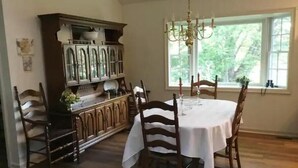 A dining room with a round table, six chairs, a chandelier, and a wooden cabinet with glass doors. - Secluded Private Guesthouse - Doylestown Twp

 (Doylestown)