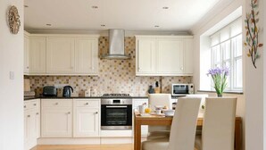 Une cuisine moderne avec des meubles blancs, un pare-feu en carreaux et un coin repas comprenant une table et des chaises en bois.