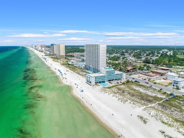 Un paysage urbain côtier avec une plage, des immeubles de grande hauteur et un ciel dégagé.