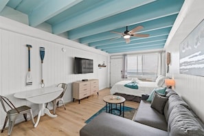 Une pièce comprenant un lit, un canapé, une table à manger avec des chaises, un ventilateur de plafond et un téléviseur.