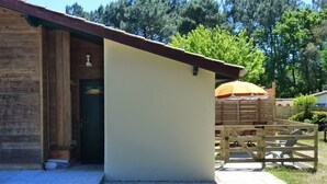 Una baita in legno con facciata color beige e un piccolo portico.