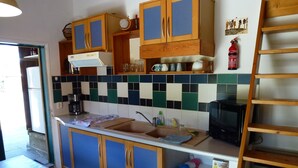 Una cucina con mobili in legno, una parete di fondo piastrellata, un lavandino e una macchina da caffè.